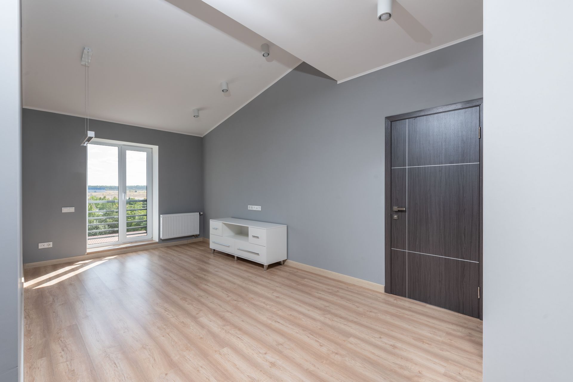 Bright and empty modern room with hardwood floors and large window view.